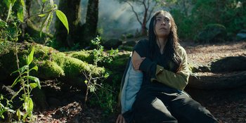 Movie still from “Sayen” (2023), directed by Alexander Witt – A woman sitting on the ground in the woods; Medium shot, Low angle
