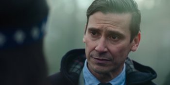Movie still from “Sayen” (2023), directed by Alexander Witt – A person wearing a jacket and tie; Close Up shot, Over the shoulder angle