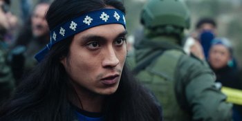 Movie still from “Sayen” (2023), directed by Alexander Witt – A person with long hair wearing a headband; Close Up shot, Over the shoulder angle