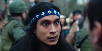 Movie still from “Sayen” (2023), directed by Alexander Witt – A person with long hair wearing a headband; Close Up shot, Over the shoulder angle