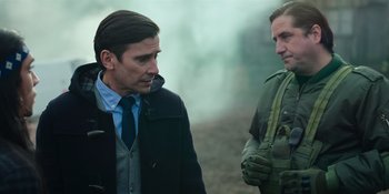 Movie still from “Sayen” (2023), directed by Alexander Witt – Two men talking to each other while standing on a dirt road; Medium shot, Over the shoulder angle