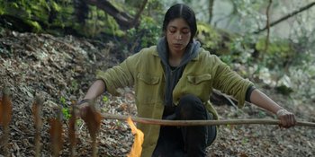 Movie still from “Sayen” (2023), directed by Alexander Witt – A person holding a stick in the forest; Medium shot, Low angle