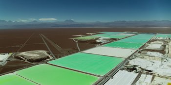 Movie still from “Sayen” (2023), directed by Alexander Witt – An aerial view of a large salt field with a mountain in the background; Extreme Wide shot, High angle