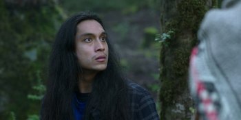 Movie still from “Sayen” (2023), directed by Alexander Witt – A man with long black hair looking up at the sky; Close Up shot, Low angle
