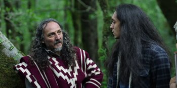 Movie still from “Sayen” (2023), directed by Alexander Witt – A man with long hair talking to a man with long black hair; Medium shot, Over the shoulder angle