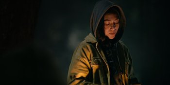 Movie still from “Sayen” (2023), directed by Alexander Witt – A person wearing a hooded jacket with a hood up; Close Up shot, Low angle