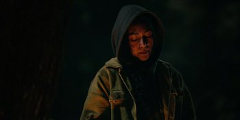 Movie still from “Sayen” (2023), directed by Alexander Witt – A person wearing a hooded jacket in the dark; Close Up shot, Over the shoulder angle