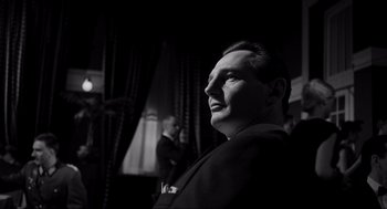Movie still from “Schindler's List” (1993), directed by Steven Spielberg – A black and white photo of a man in a suit; Close Up shot, Low angle