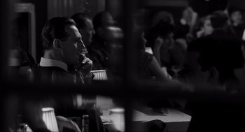 Movie still from “Schindler's List” (1993), directed by Steven Spielberg – A group of people sitting at a table with drinks; Medium shot, Over the shoulder angle