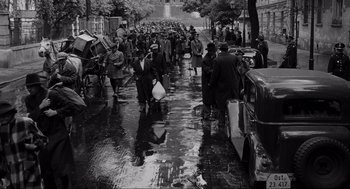 Movie still from “Schindler's List” (1993), directed by Steven Spielberg – A black and white photo of people walking down a wet street; Extreme Wide shot, High angle