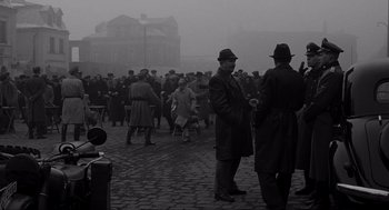 Movie still from “Schindler's List” (1993), directed by Steven Spielberg – A group of men standing on top of a cobblestone street; Wide shot, High angle