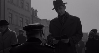 Movie still from “Schindler's List” (1993), directed by Steven Spielberg – A man in a hat and a coat and a man in a hat and a coat; Medium shot, Low angle