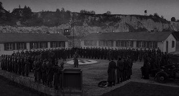Movie still from “Schindler's List” (1993), directed by Steven Spielberg – A group of men standing in front of each other in a circle; Extreme Wide shot, High angle