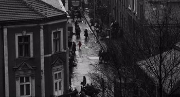 Movie still from “Schindler's List” (1993), directed by Steven Spielberg – A black - and - white photo of people walking down a street; Extreme Wide shot, High angle