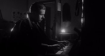 Movie still from “Schindler's List” (1993), directed by Steven Spielberg – A man is playing the piano in a dark room; Close Up shot, Low angle