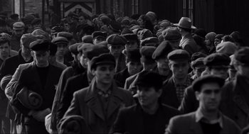 Movie still from “Schindler's List” (1993), directed by Steven Spielberg – Black and white photograph of a crowd of men wearing hats; Medium shot, High angle