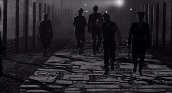 Movie still from “Schindler's List” (1993), directed by Steven Spielberg – A black and white photo of a group of men walking down a street; Wide shot, High angle