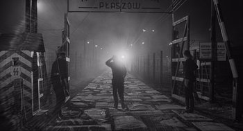 Movie still from “Schindler's List” (1993), directed by Steven Spielberg – A man standing in the middle of a train track; Wide shot, Over the shoulder angle