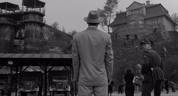 Movie still from “Schindler's List” (1993), directed by Steven Spielberg – A black and white photo of a man in a suit and hat; Wide shot, High angle