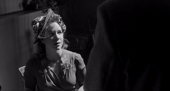 Movie still from “Schindler's List” (1993), directed by Steven Spielberg – A woman with a hat sitting in front of another woman; Close Up shot, Over the shoulder angle