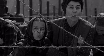 Movie still from “Schindler's List” (1993), directed by Steven Spielberg – A woman and a child sitting next to a barbed wire fence; Medium shot, Low angle