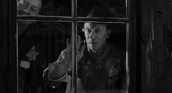 Movie still from “Schindler's List” (1993), directed by Steven Spielberg – A man smoking a pipe while looking out of a window; Medium shot, Over the shoulder angle