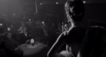 Movie still from “Schindler's List” (1993), directed by Steven Spielberg – A woman standing in front of a group of people; Medium shot, Over the shoulder angle