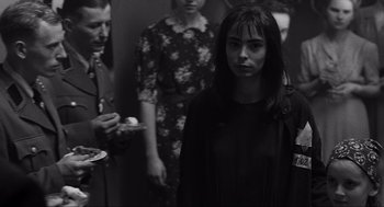 Movie still from “Schindler's List” (1993), directed by Steven Spielberg – Black and white photograph of a woman in front of a group of people; Close Up shot, Over the shoulder angle