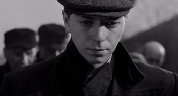 Movie still from “Schindler's List” (1993), directed by Steven Spielberg – A young man in a hat and a coat; Close Up shot, High angle