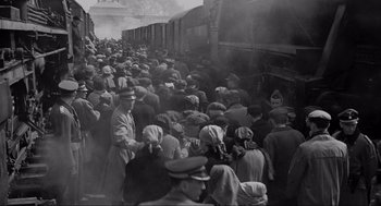 Movie still from “Schindler's List” (1993), directed by Steven Spielberg – A large group of people standing next to a train; Extreme Wide shot, High angle