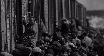 Movie still from “Schindler's List” (1993), directed by Steven Spielberg – A group of people standing next to each other on a train platform; Wide shot, High angle