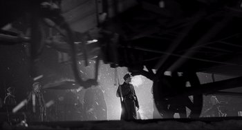 Movie still from “Schindler's List” (1993), directed by Steven Spielberg – A man holding a rifle standing in the middle of a building; Wide shot, Low angle