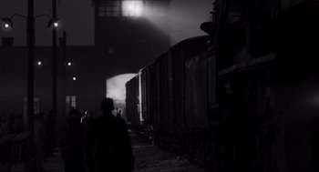 Movie still from “Schindler's List” (1993), directed by Steven Spielberg – People are walking on the train tracks at night; Extreme Wide shot, Over the shoulder angle