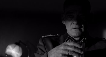 Movie still from “Schindler's List” (1993), directed by Steven Spielberg – A black and white photo of a man in uniform; Close Up shot, Over the shoulder angle