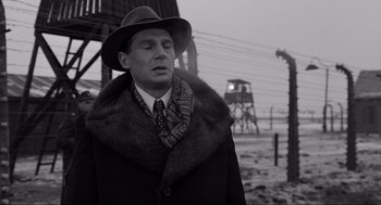 Movie still from “Schindler's List” (1993), directed by Steven Spielberg – A man wearing a hat and a fur coat standing in front of barbed wire; Close Up shot, Over the shoulder angle