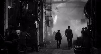 Movie still from “Schindler's List” (1993), directed by Steven Spielberg – A black and white photo of two men walking through a factory; Wide shot, Low angle