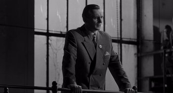 Movie still from “Schindler's List” (1993), directed by Steven Spielberg – A black and white photo of a man in a suit and tie; Medium shot, Low angle