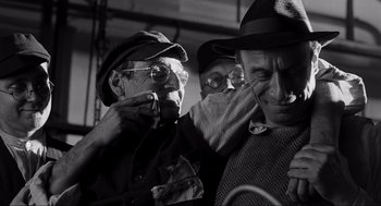 Movie still from “Schindler's List” (1993), directed by Steven Spielberg – A group of men standing next to each other in a room; Medium shot, Over the shoulder angle