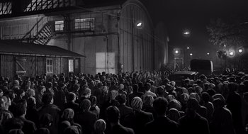 Movie still from “Schindler's List” (1993), directed by Steven Spielberg – A crowd of people standing in front of a building at night; Extreme Wide shot, High angle
