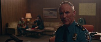 Movie still from “BlacKkKlansman” (2018), directed by Spike Lee – A man sitting in front of a woman in a living room; Medium shot, Over the shoulder angle