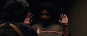 Movie still from “BlacKkKlansman” (2018), directed by Spike Lee – A man in a striped sweater talking to another man; Medium shot, Over the shoulder angle