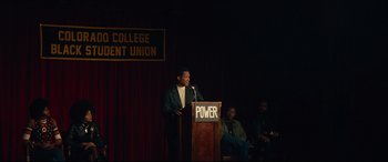 Movie still from “BlacKkKlansman” (2018), directed by Spike Lee – A man standing at a podium speaking to a crowd of onlookers; Wide shot, Low angle