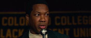 Movie still from “BlacKkKlansman” (2018), directed by Spike Lee – A person holding a microphone; Close Up shot, High angle