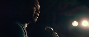 Movie still from “BlacKkKlansman” (2018), directed by Spike Lee – A person speaking into a microphone; Close Up shot, Low angle