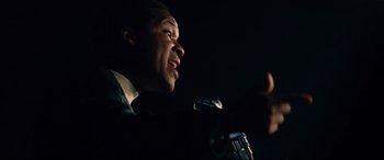 Movie still from “BlacKkKlansman” (2018), directed by Spike Lee – A man in a suit is speaking into a microphone; Close Up shot, Low angle