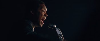 Movie still from “BlacKkKlansman” (2018), directed by Spike Lee – A man is speaking into a microphone on a stage; Close Up shot, Low angle