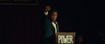 Movie still from “BlacKkKlansman” (2018), directed by Spike Lee – A man standing at a podium giving a speech; Medium shot, Low angle