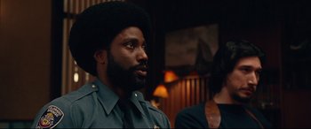 Movie still from “BlacKkKlansman” (2018), directed by Spike Lee – A man in a police uniform looking to his left; Close Up shot, Over the shoulder angle