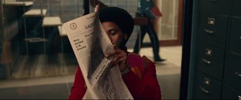 Movie still from “BlacKkKlansman” (2018), directed by Spike Lee – A man reading a newspaper while sitting on a bench; Close Up shot, Over the shoulder angle