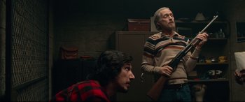 Movie still from “BlacKkKlansman” (2018), directed by Spike Lee – Two men are sitting in a dimly - lit room; Medium shot, Low angle